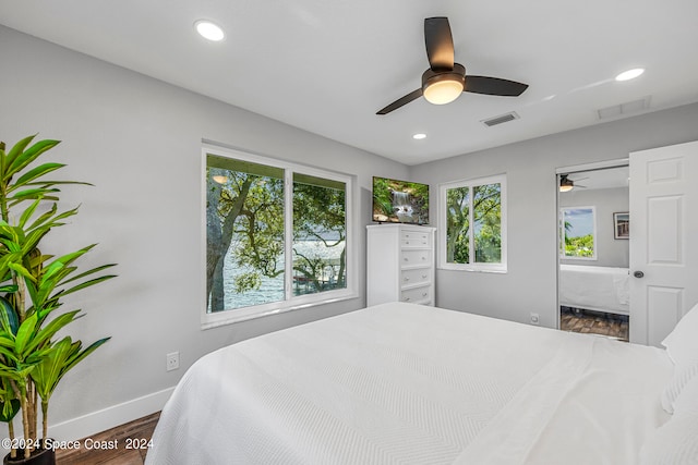 bedroom with dark hardwood / wood-style flooring, ceiling fan, and multiple windows