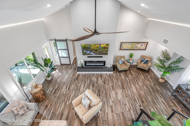 unfurnished living room with ceiling fan, dark hardwood / wood-style floors, and high vaulted ceiling