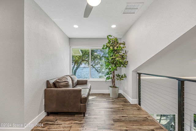 sitting room featuring dark wood-type flooring, ceiling fan, and a water view