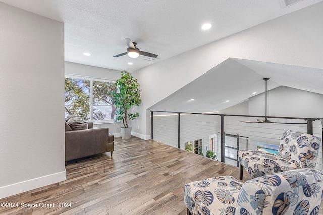 sitting room featuring ceiling fan, wood-type flooring, and vaulted ceiling