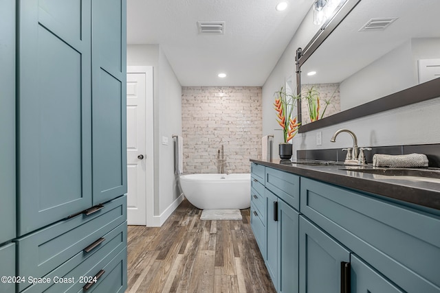 bathroom featuring vanity, a bath, hardwood / wood-style flooring, and a textured ceiling