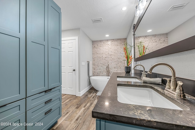 bathroom with a textured ceiling, vanity, a bathing tub, and hardwood / wood-style flooring