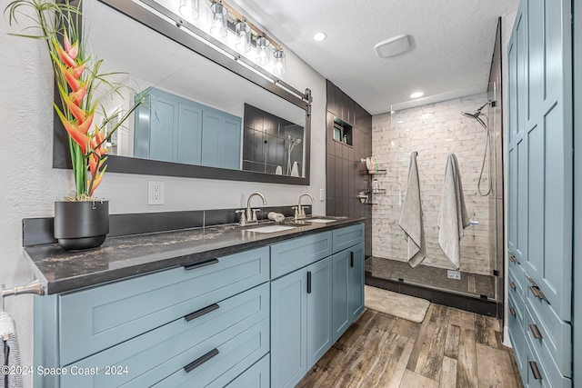 bathroom with tiled shower, vanity, wood-type flooring, and a textured ceiling