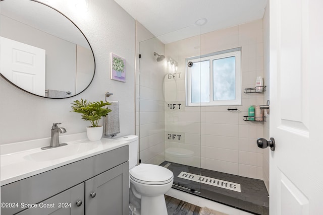 bathroom with vanity, toilet, a tile shower, and hardwood / wood-style floors