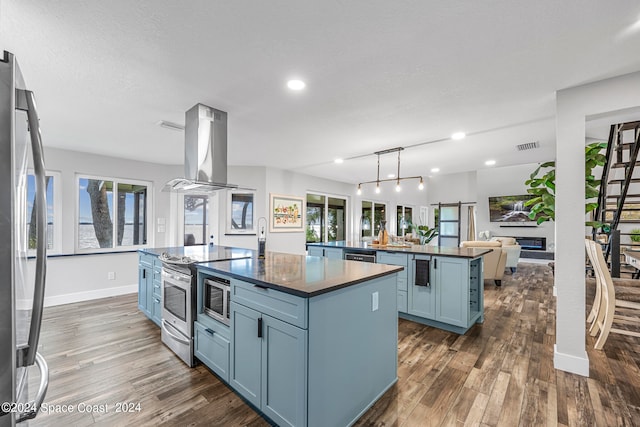 kitchen featuring island range hood, stainless steel appliances, dark hardwood / wood-style floors, and a kitchen island with sink