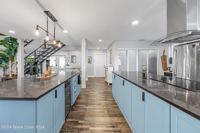 kitchen with wall chimney exhaust hood, dark hardwood / wood-style flooring, a spacious island, blue cabinetry, and black electric cooktop