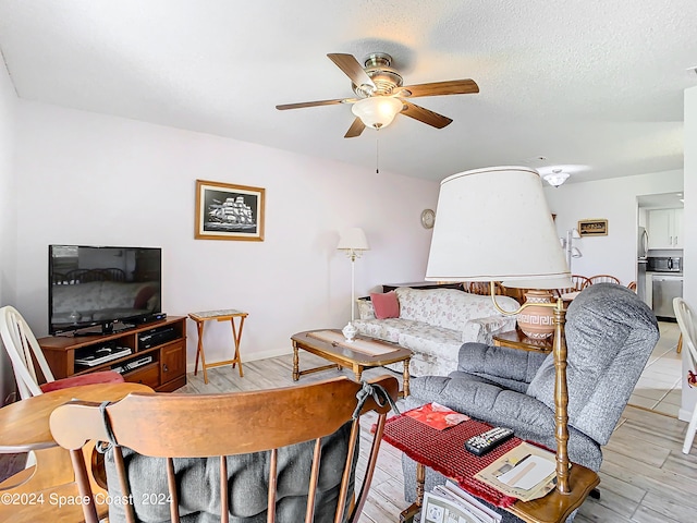 living room featuring a textured ceiling, light hardwood / wood-style flooring, and ceiling fan