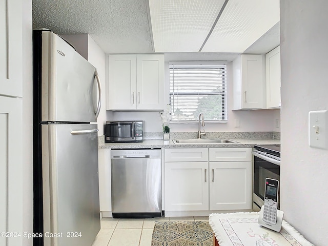 kitchen with a textured ceiling, stainless steel appliances, sink, white cabinetry, and light tile patterned flooring