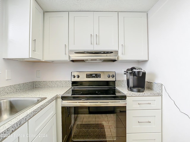 kitchen featuring a textured ceiling, stainless steel electric stove, sink, tile patterned floors, and white cabinetry