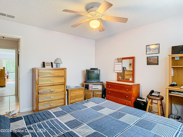 tiled bedroom featuring ceiling fan and a textured ceiling