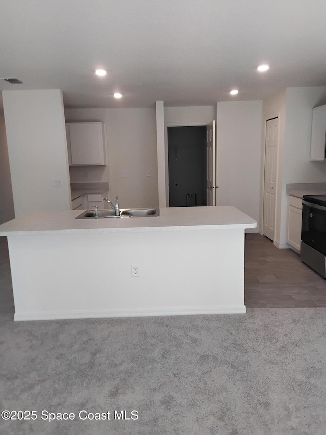 kitchen with sink, white cabinetry, light carpet, electric range, and a kitchen island