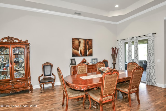 dining room with hardwood / wood-style floors, a tray ceiling, and ornamental molding