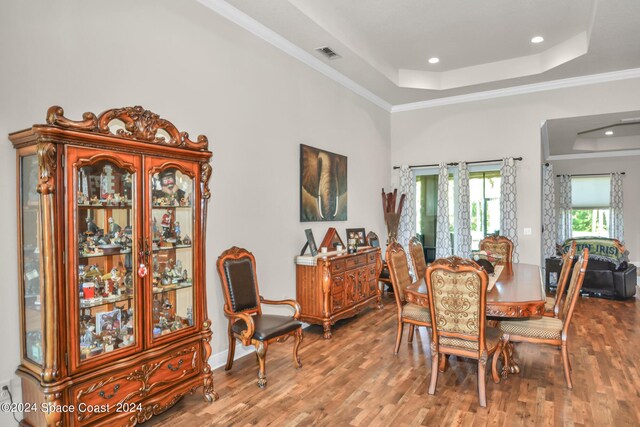 dining area featuring crown molding, wood-type flooring, and a tray ceiling