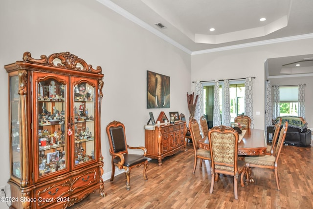 dining space featuring visible vents, crown molding, a tray ceiling, and wood finished floors