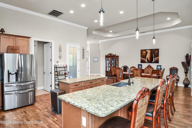 kitchen with a large island, a tray ceiling, a sink, and stainless steel fridge with ice dispenser