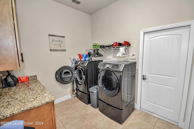 laundry room featuring washing machine and clothes dryer, light tile patterned floors, cabinet space, visible vents, and baseboards