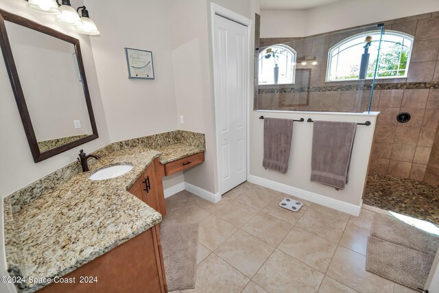 bathroom with vanity, tiled shower, and tile patterned flooring