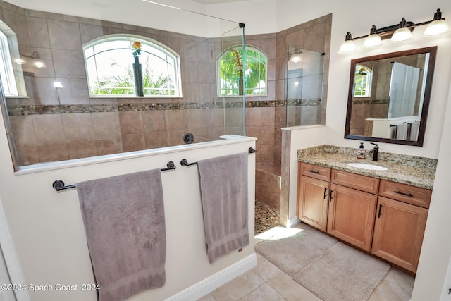 bathroom with tiled shower, vanity, and tile patterned flooring