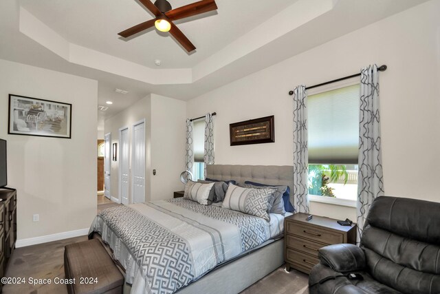 bedroom with ceiling fan, a closet, a tray ceiling, and connected bathroom