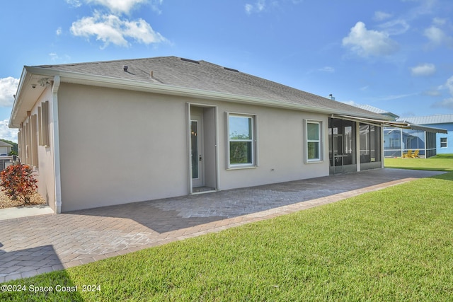 back of house with a sunroom, a yard, a patio, and stucco siding