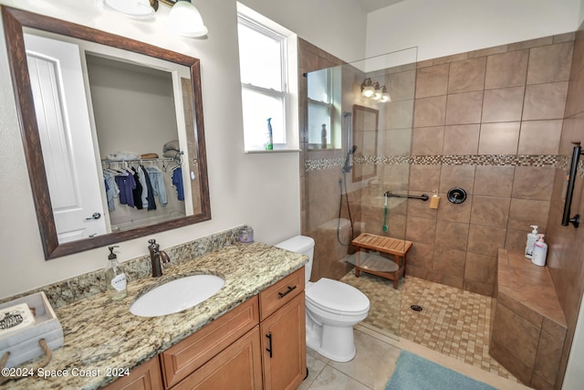 bathroom featuring vanity, toilet, tiled shower, and tile patterned floors