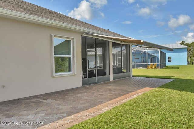 rear view of property with a yard, a patio, and a sunroom