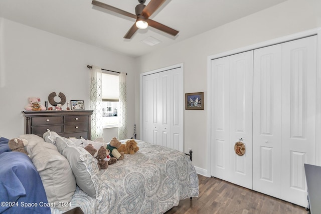 bedroom featuring multiple closets, visible vents, ceiling fan, and wood finished floors