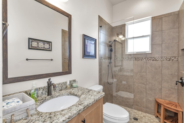 bathroom with tiled shower, vanity, and toilet