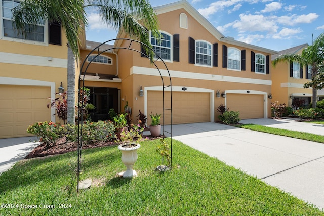 view of front of house featuring driveway, an attached garage, a front lawn, and stucco siding