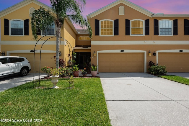 view of front of house with driveway, a front lawn, an attached garage, and stucco siding