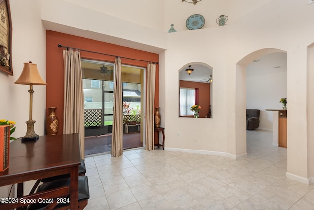 foyer entrance with arched walkways, ceiling fan, and baseboards