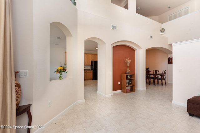 corridor with a towering ceiling, visible vents, and baseboards