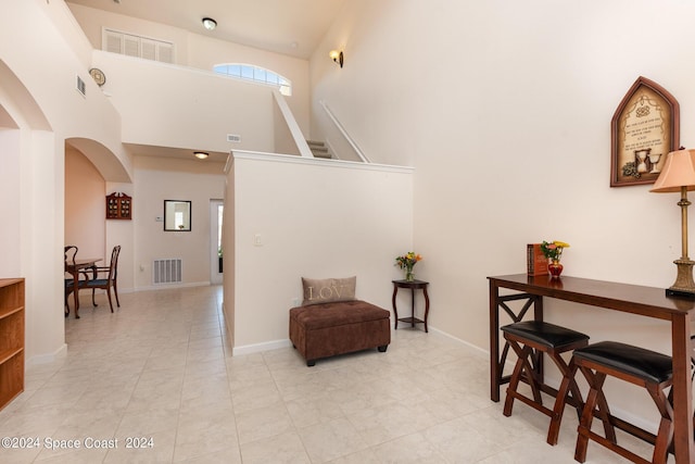 sitting room featuring arched walkways, a high ceiling, visible vents, and baseboards