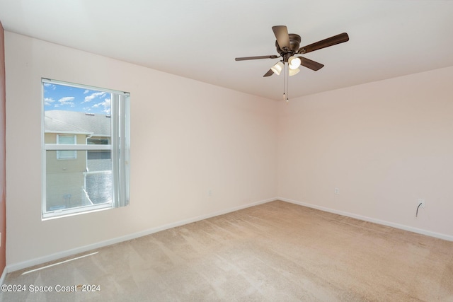 spare room with a ceiling fan, light colored carpet, and baseboards