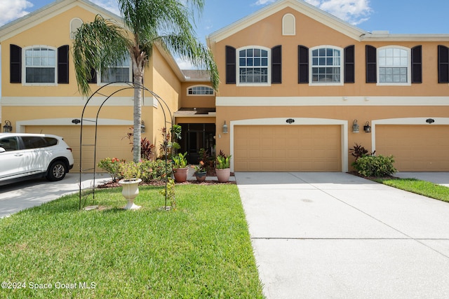 view of front of house with driveway, an attached garage, a front lawn, and stucco siding