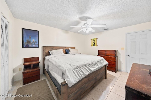 bedroom featuring a closet, a textured ceiling, light tile patterned floors, and ceiling fan