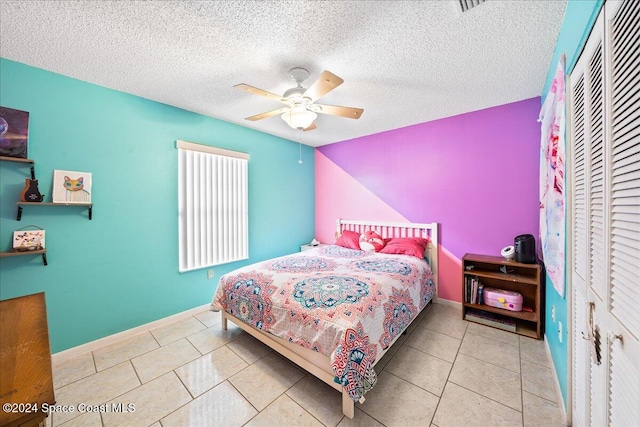 tiled bedroom with a closet, a textured ceiling, and ceiling fan