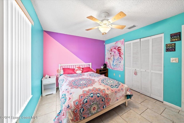 bedroom with a closet, a textured ceiling, light tile patterned floors, and ceiling fan