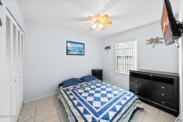 bedroom featuring a closet, ceiling fan, a textured ceiling, and light tile patterned flooring