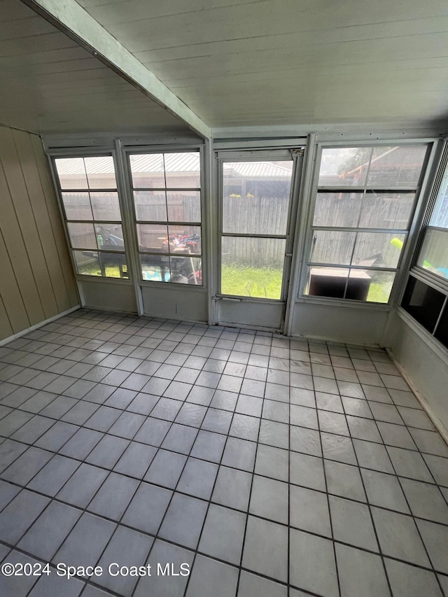 unfurnished sunroom featuring a healthy amount of sunlight, beamed ceiling, and wooden ceiling