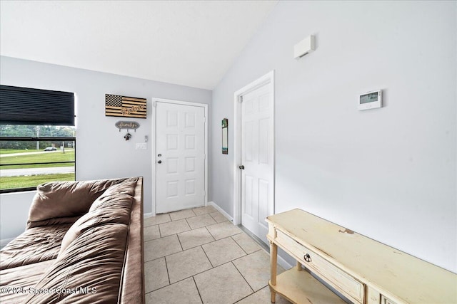 entrance foyer with lofted ceiling, light tile patterned flooring, and baseboards