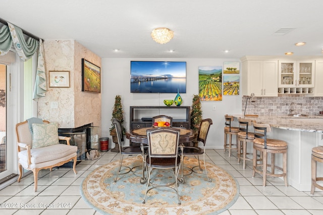 dining space featuring a multi sided fireplace, light tile patterned floors, and sink