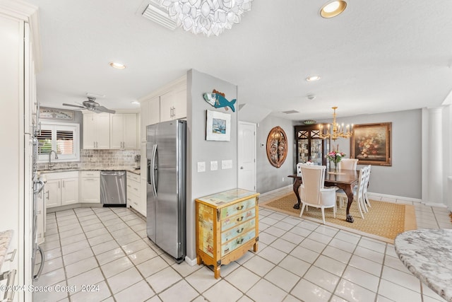 kitchen featuring ceiling fan with notable chandelier, backsplash, light tile patterned floors, appliances with stainless steel finishes, and white cabinets