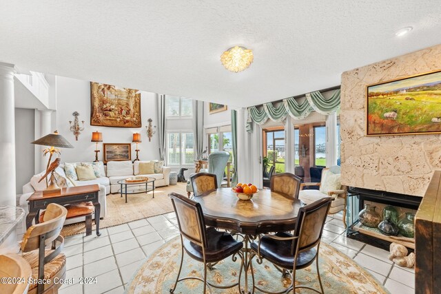 dining space featuring a textured ceiling, light tile patterned flooring, and a fireplace