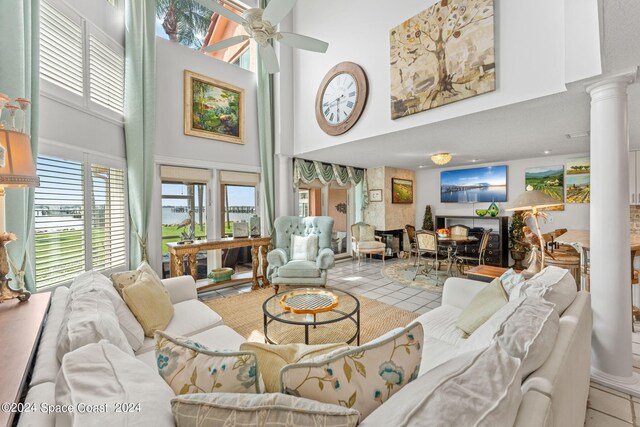 tiled living room with ceiling fan, decorative columns, and a towering ceiling