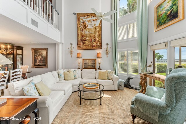 carpeted living room featuring a towering ceiling, a healthy amount of sunlight, and ceiling fan