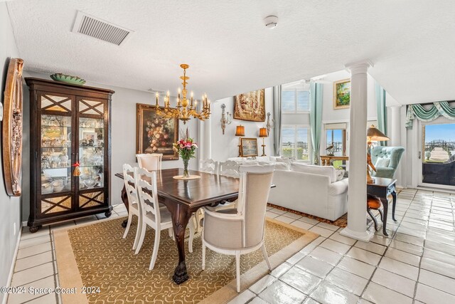 tiled dining room with a textured ceiling, a chandelier, and decorative columns