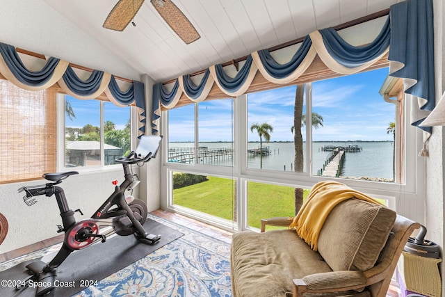 exercise room with lofted ceiling, a healthy amount of sunlight, ceiling fan, and a water view