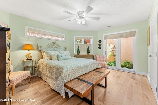 bedroom with light wood finished floors, visible vents, baseboards, ceiling fan, and a textured ceiling