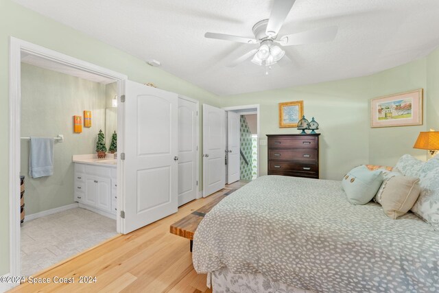 bedroom with light hardwood / wood-style flooring, ceiling fan, sink, and ensuite bath